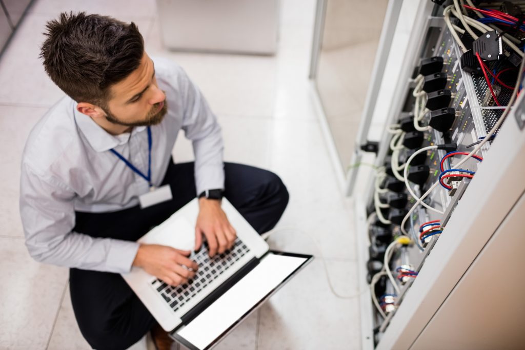 Technician using a laptop whilst analysing a server
