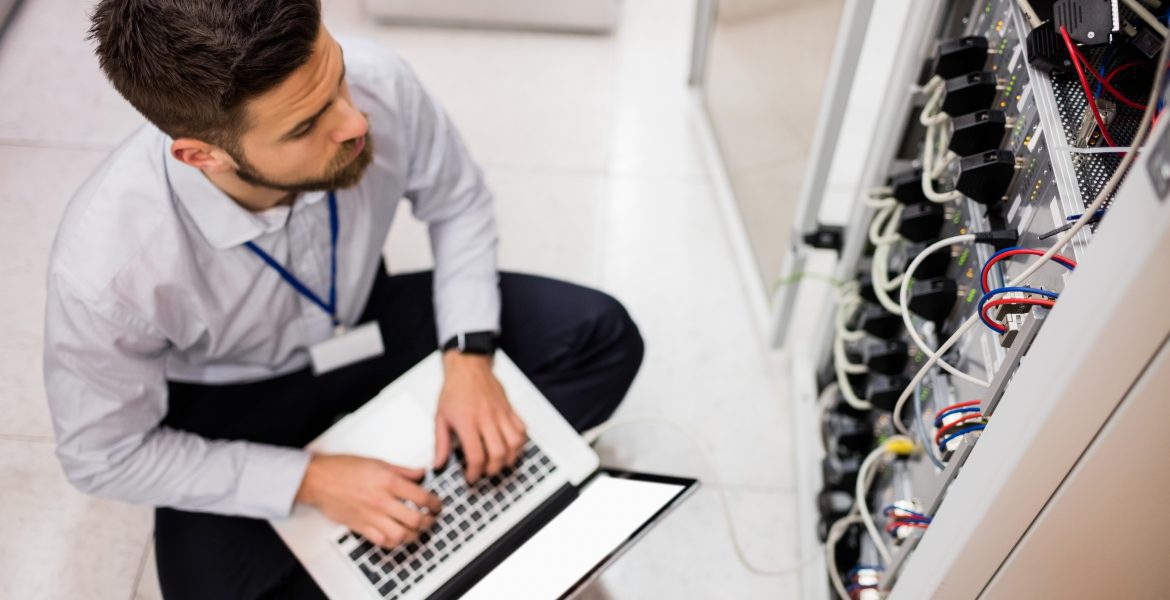 Technician Using Laptop While Analyzing Server