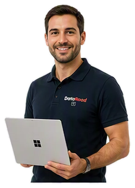 Smiling man in a navy polo shirt holding a silver laptop, standing with a casual pose.