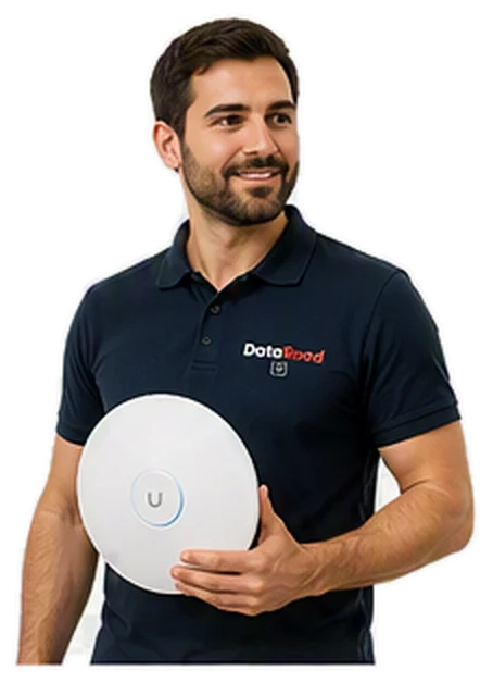 Bearded man in a navy polo shirt holding a round white wireless device with a blue ring and a 'U' button, wearing a DotaRoad logo polo.